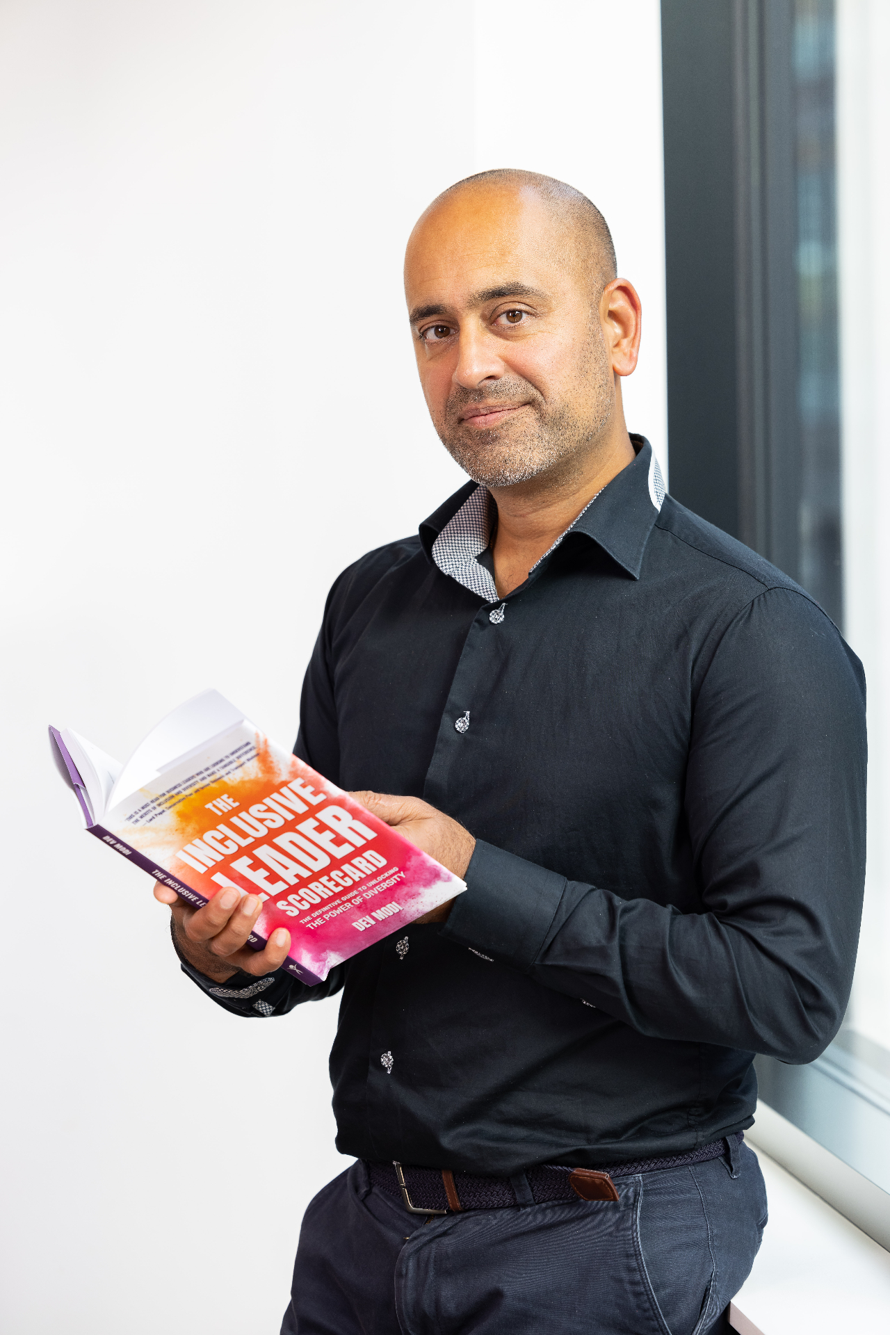 Portrait of Dev Modi holding his book The Inclusive Leader Scorecard