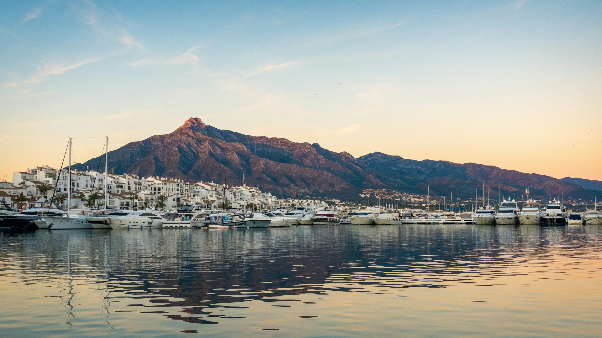 Aerial view of Marbella's Mediterranean coastline with luxury yachts and mountains